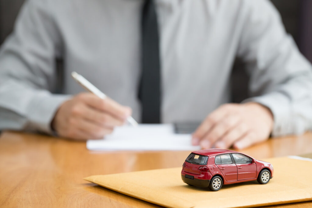 Man signing contract with toy car on table