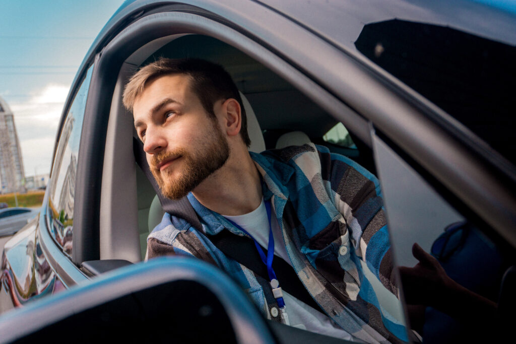 Young bearded male passenger looking out the window of a car.