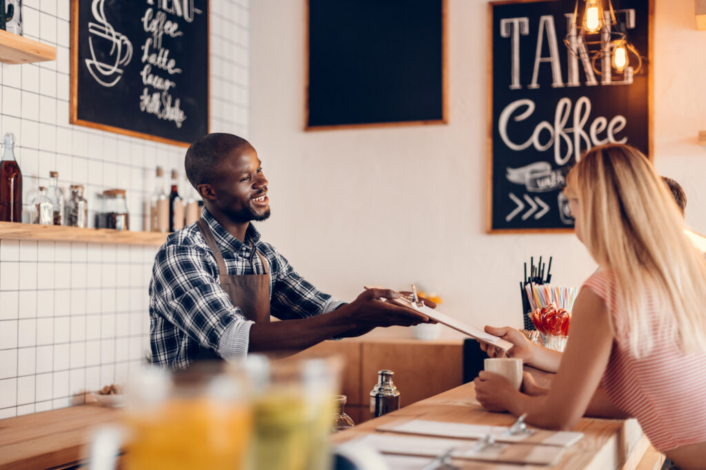 barista giving menu to client in cafe