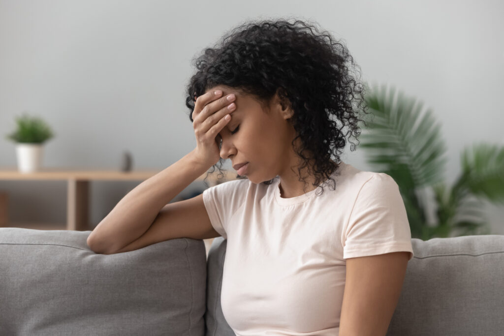 Depressed black young woman sitting on sofa